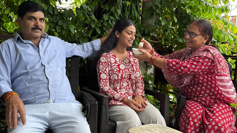 साक्षी को सफलता पर मिठाई खिलाते मां और पिता।