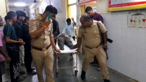 बांदा में भाइयों में गोलीबारी के बाद घायल को अस्पताल ले जाते पुलिस कर्मी।
