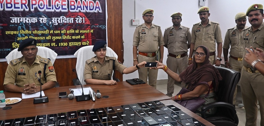 बांदा में IPS मेविस टाक महिला को मोबाइल लौटाते हुए