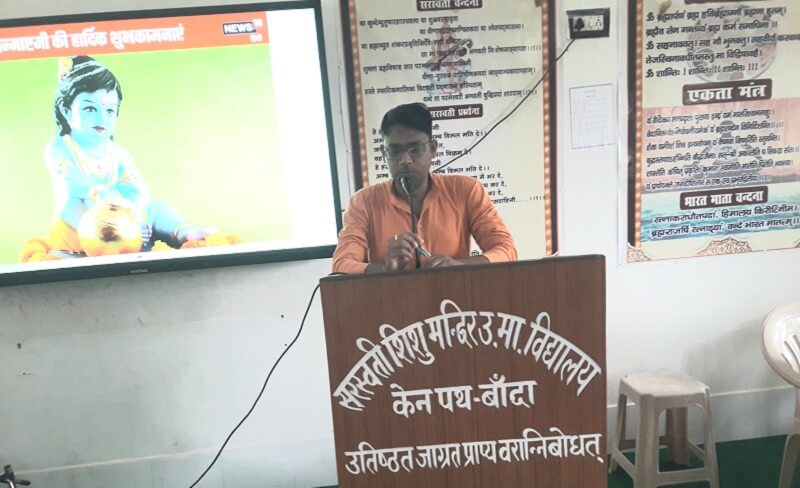 बांदा सरस्वती स्कूल में जन्माष्टमी कार्यक्रम में बोलते आचार्य