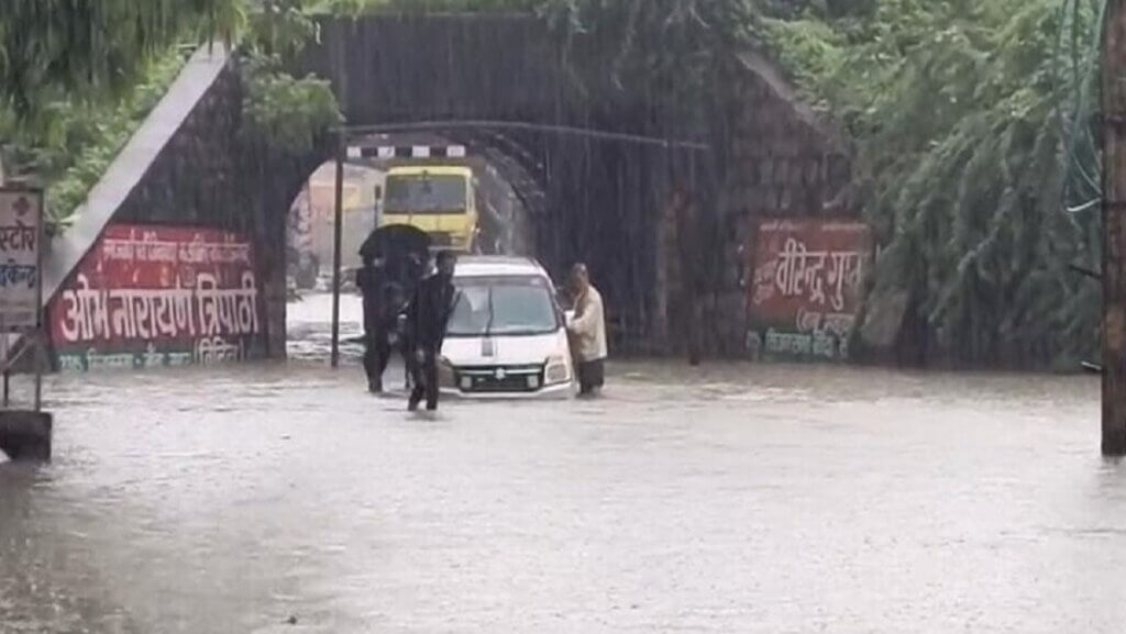 बांदा में भीषण बारिश के बीच लोहिया पुल से गुजरते लोग। 